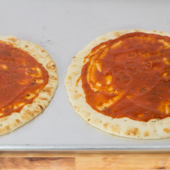 two pieces of naan with tomato sauce on top