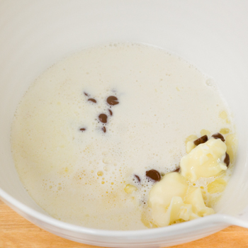 Chocolate chips, cream, and margarine combined in a bowl.