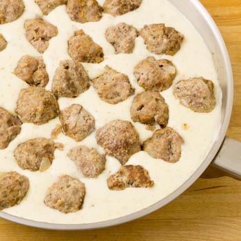 adding meatballs to sauce