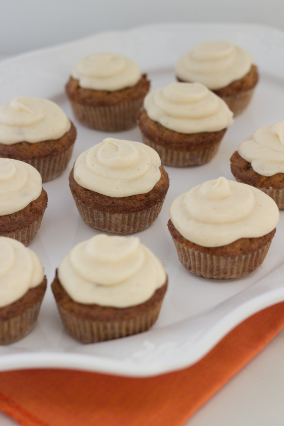 Carrot cake muffins with cream cheese frosting on plate.